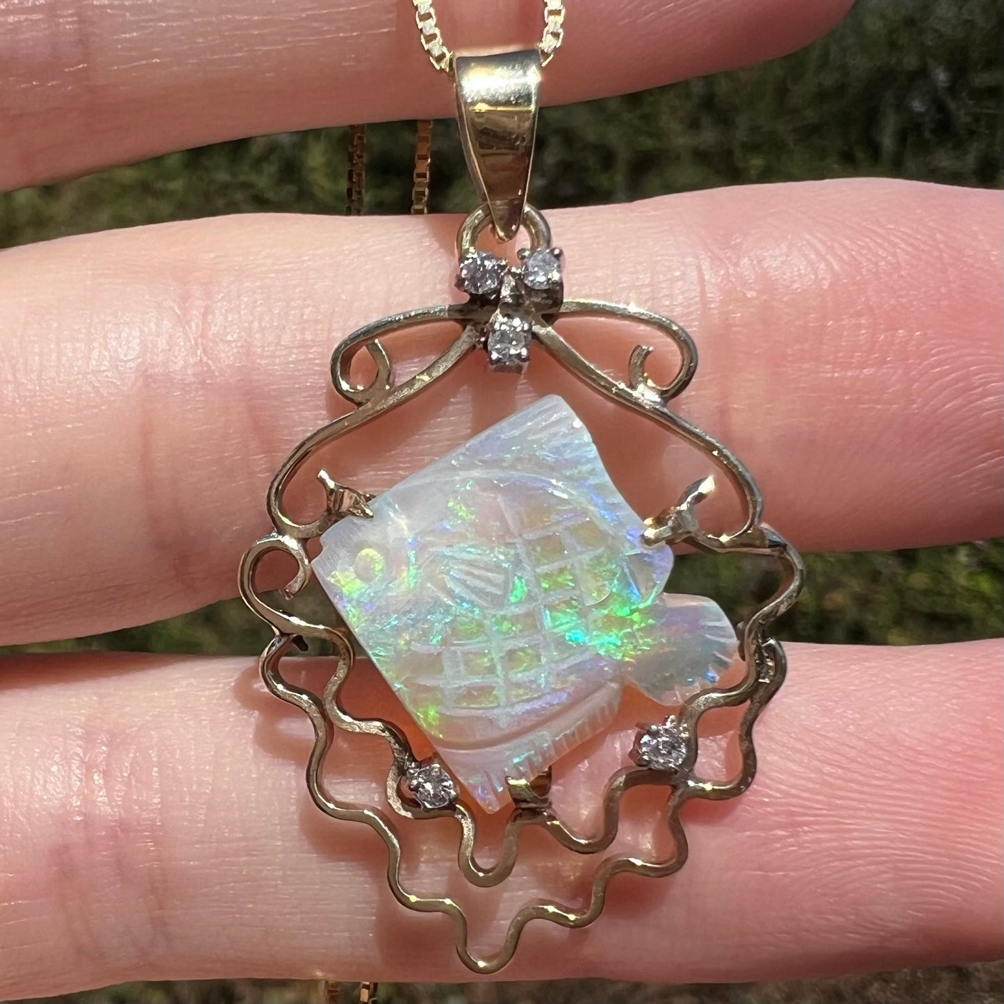 Carved Australian opal fish pendant with nautical motif featuring diamond bubbles and 14k gold waves shown close-up in sunlight