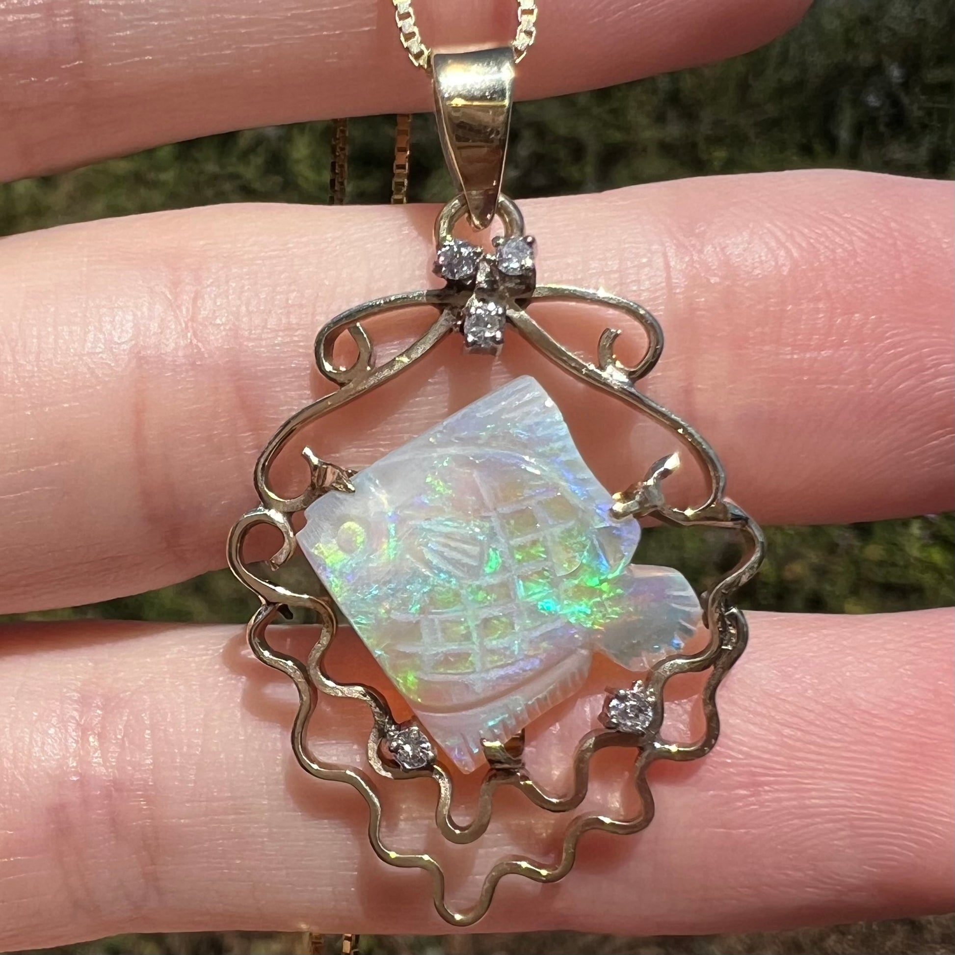 Carved Australian opal fish pendant with nautical motif featuring diamond bubbles and 14k gold waves shown close-up in sunlight