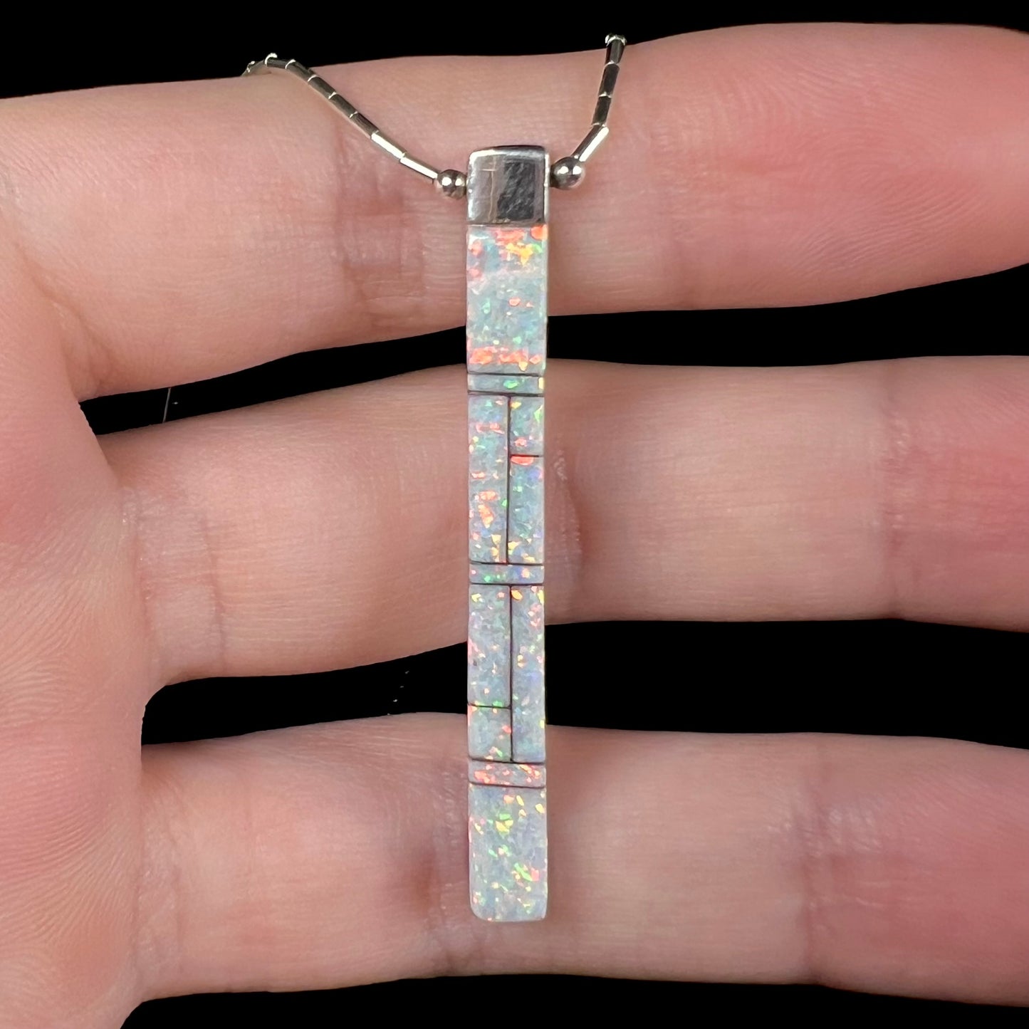 A macro close-up of the opal side of the Navajo inlay pendant, showing bright orange pinfire.