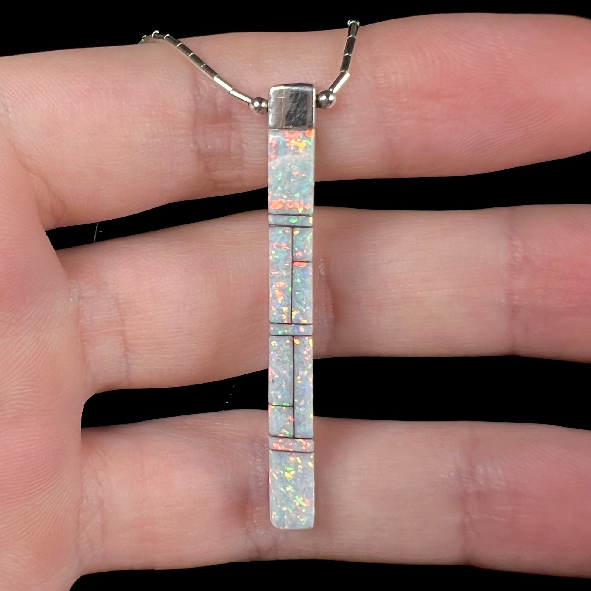 A macro close-up of the opal side of the Navajo inlay pendant, showing bright orange pinfire.