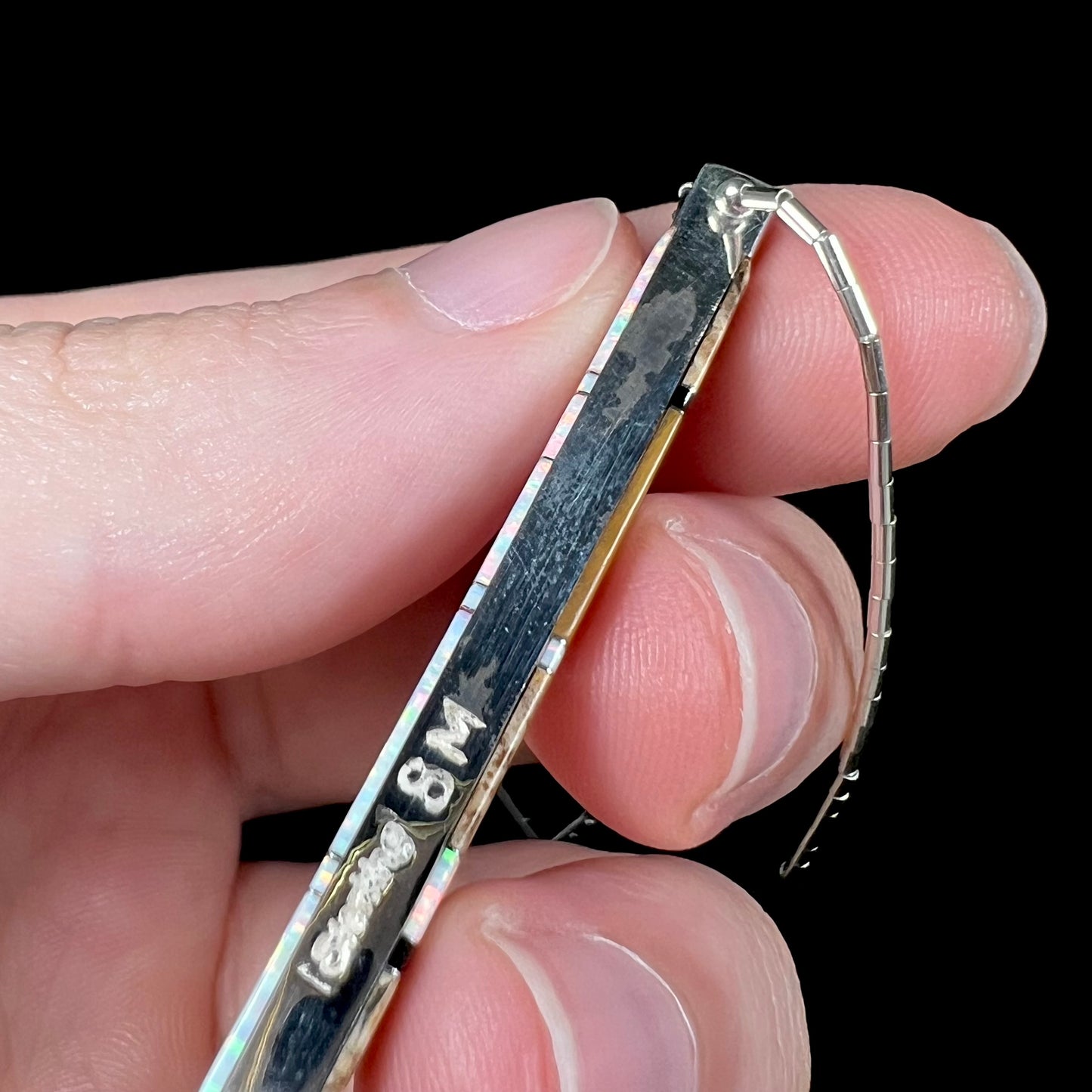 A macro close-up of the side of the Navajo inlay pendant, showing silver discoloration and the ‘Sterling SM’ stamp.