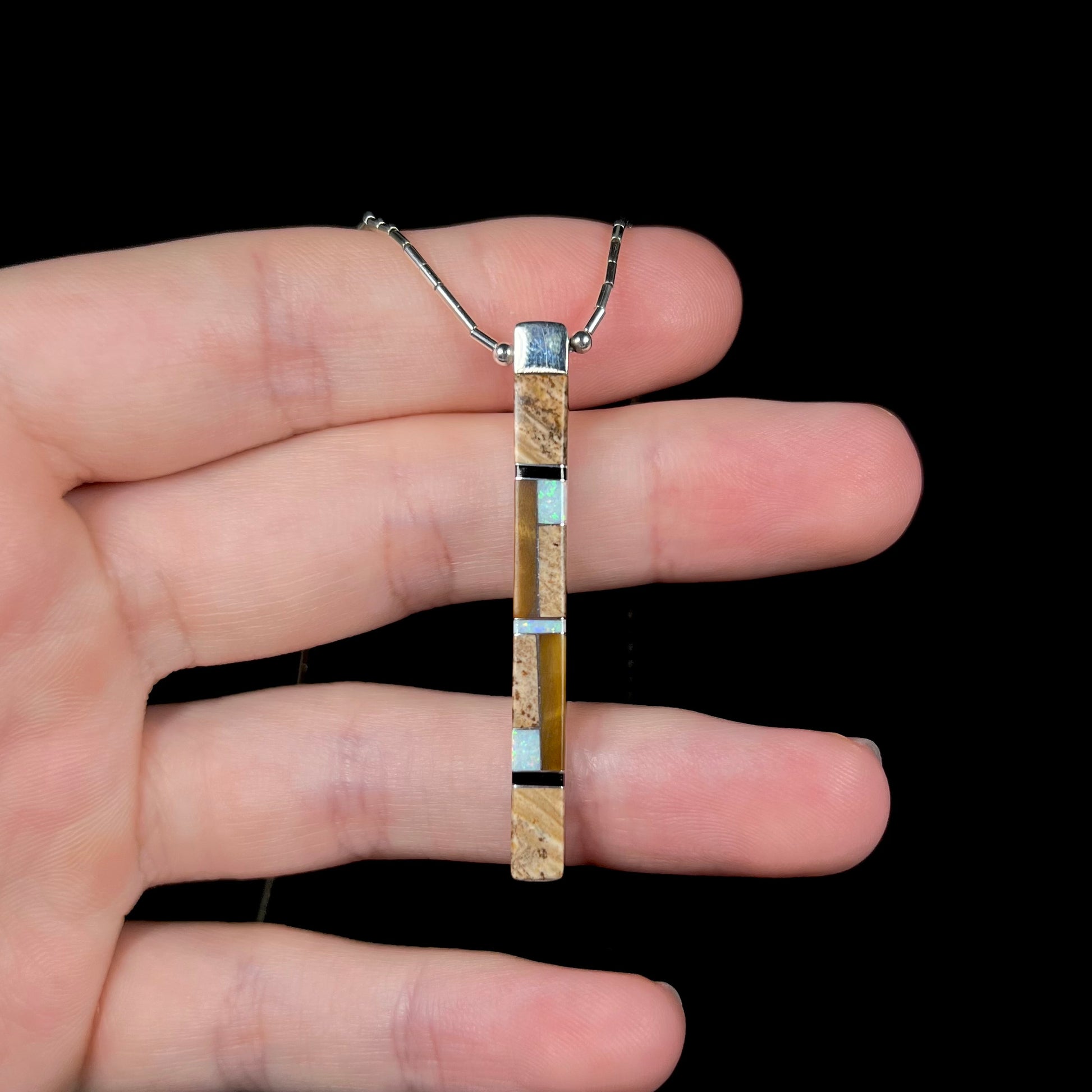 A Navajo inlay pendant resting on fingers, showing the jasper inlay side.