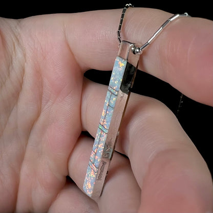 A side view of the Navajo inlay pendant, showing bright orange pinfire on the opal side.