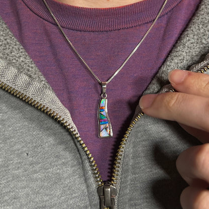 A Navajo-made silver opal inlay necklace worn around a neck against a purple shirt.