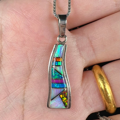 Close-up of a Navajo opal inlay pendant made from sterling silver, held in a hand.