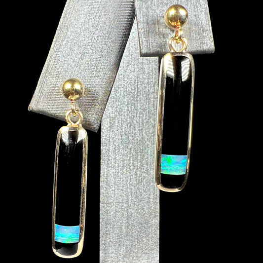 A pair of onyx and opal inlay dangle earrings cast in yellow gold, shown from the front view.
