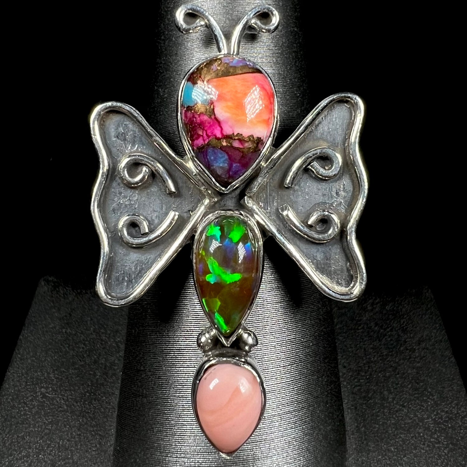 A sterling silver butterfly ring set with lab-created and pink Peruvian opals, shown from the front.
