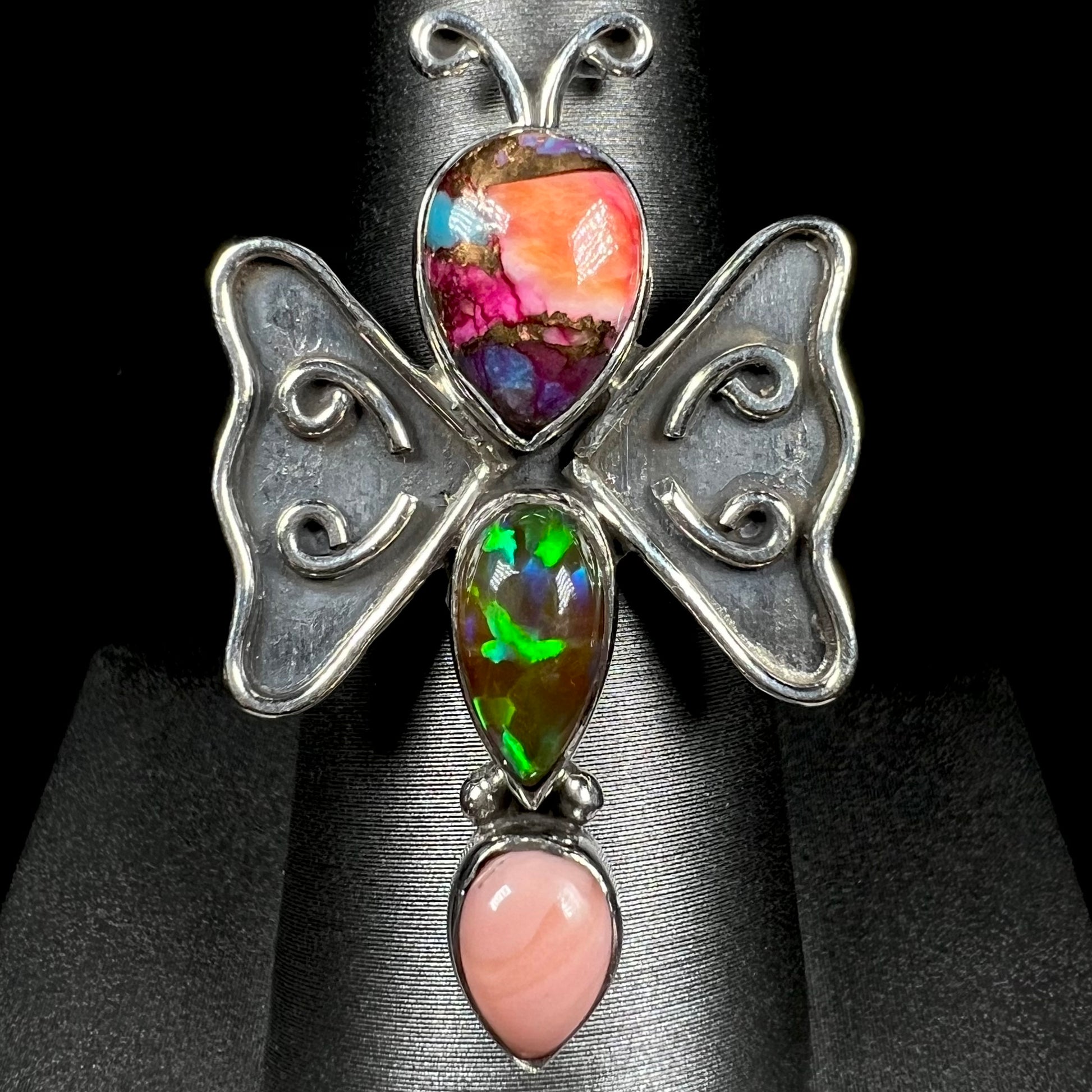 A sterling silver butterfly ring set with lab-created and pink Peruvian opals, shown from the front.