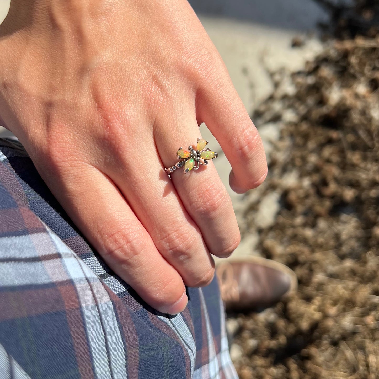 A sterling silver Ethiopian opal butterfly ring worn on a hand as the hand rests on the model's hip.