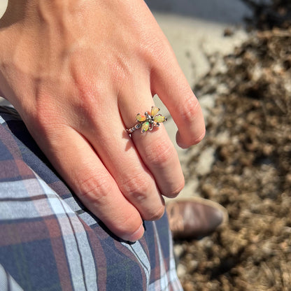 A sterling silver Ethiopian opal butterfly ring worn on a hand as the hand rests on the model's hip.