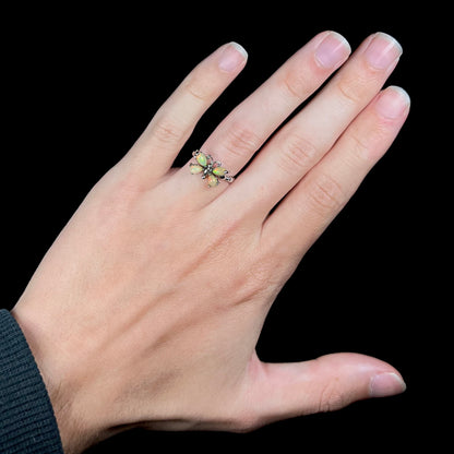 A sterling silver Ethiopian opal butterfly ring shown on a hand against a black background.