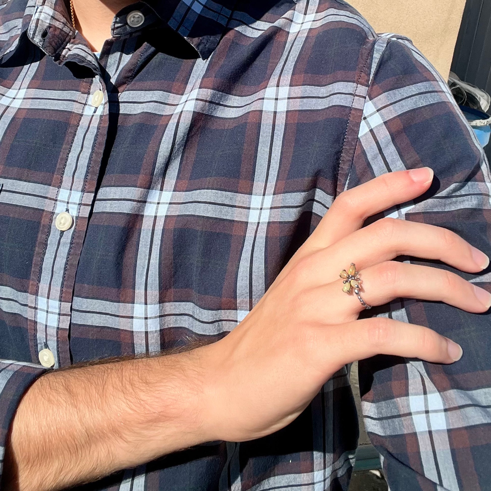 A sterling silver Ethiopian opal butterfly ring worn on a hand as the hand rests on the model's opposing shoulder.