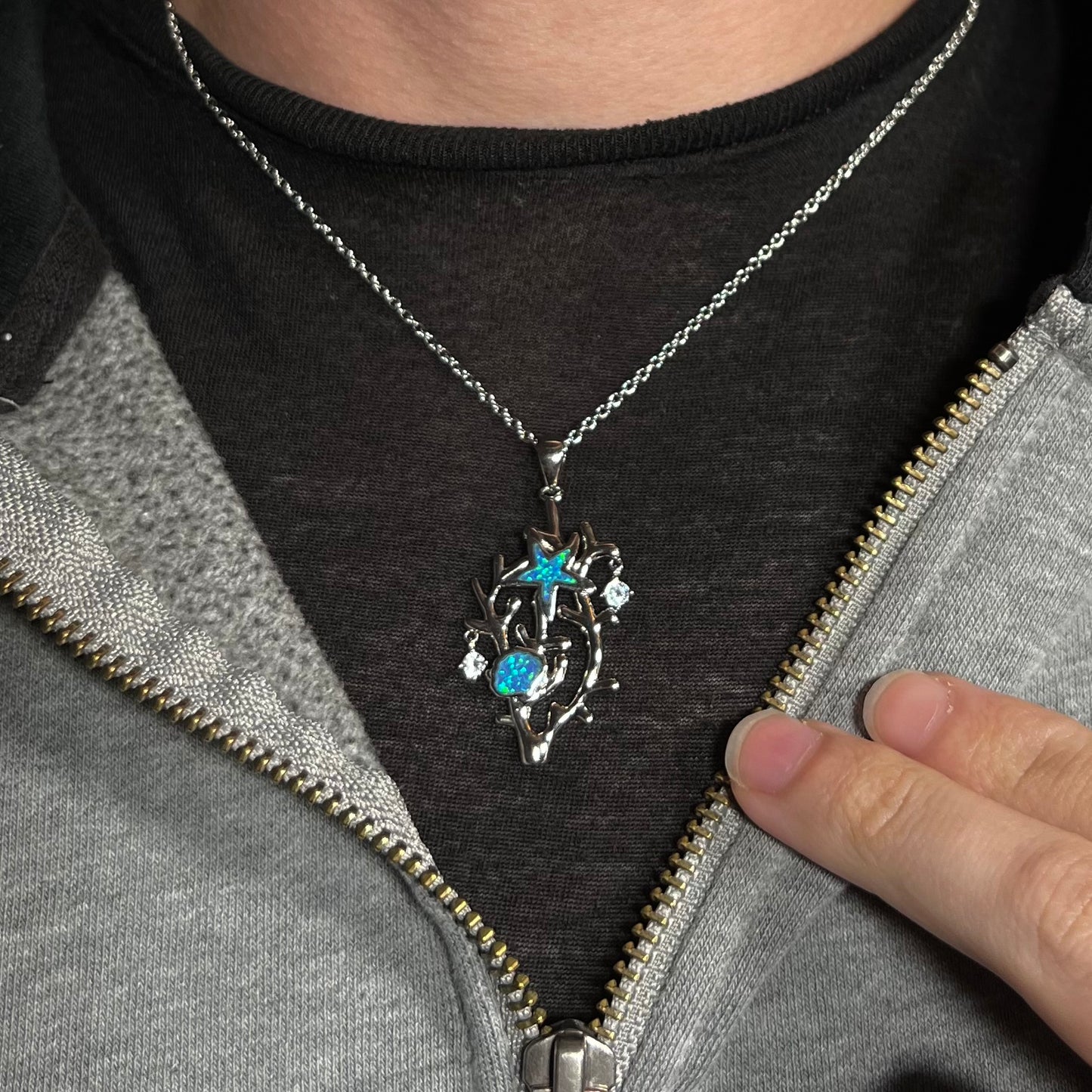 A silver plated coral reef necklace with blue lab-created opal inlay and CZ accents worn around a neck.