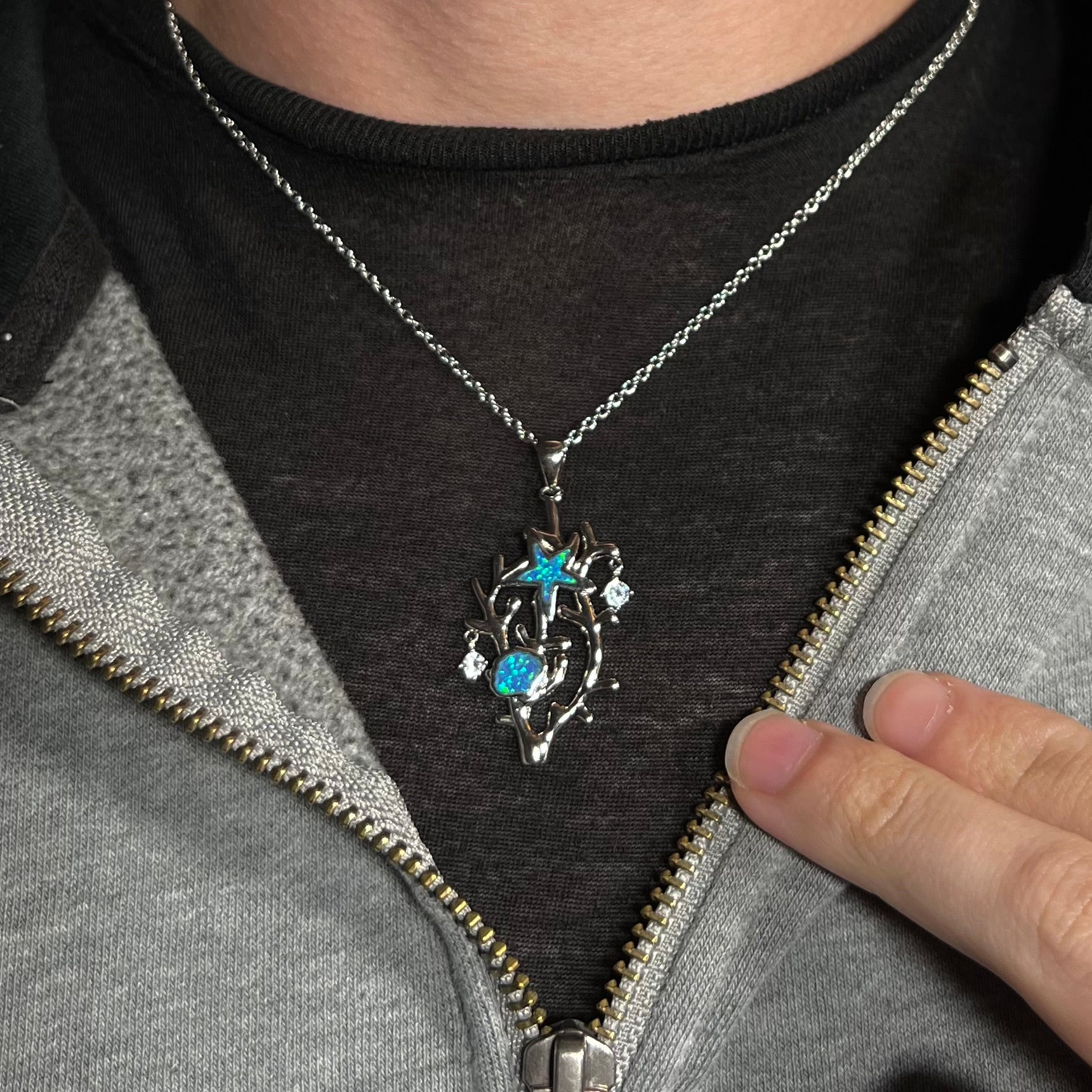 A silver plated coral reef necklace with blue lab-created opal inlay and CZ accents worn around a neck.