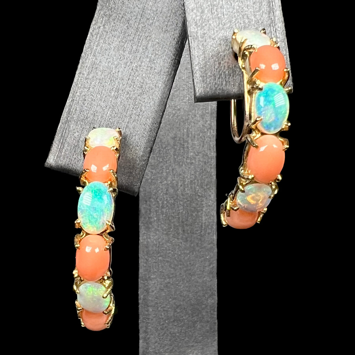 Close-up of a pair of vintage 14k gold six-stone Australian crystal opal and coral non-pierced, screw back semi-hoop earrings on earring display