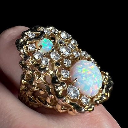 An opal and cubic zirconia ring with a large, 1970s-inspired brutalist design shown close-up from angle on finger.