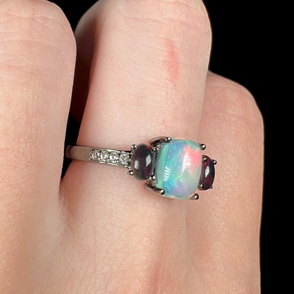 Sterling silver ring with black rhodium finish featuring three Ethiopian opals, worn on finger
