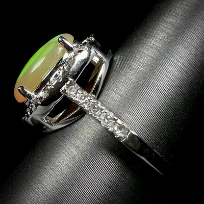 Side profile view of a sterling silver Ethiopian fire opal ring with a CZ halo.