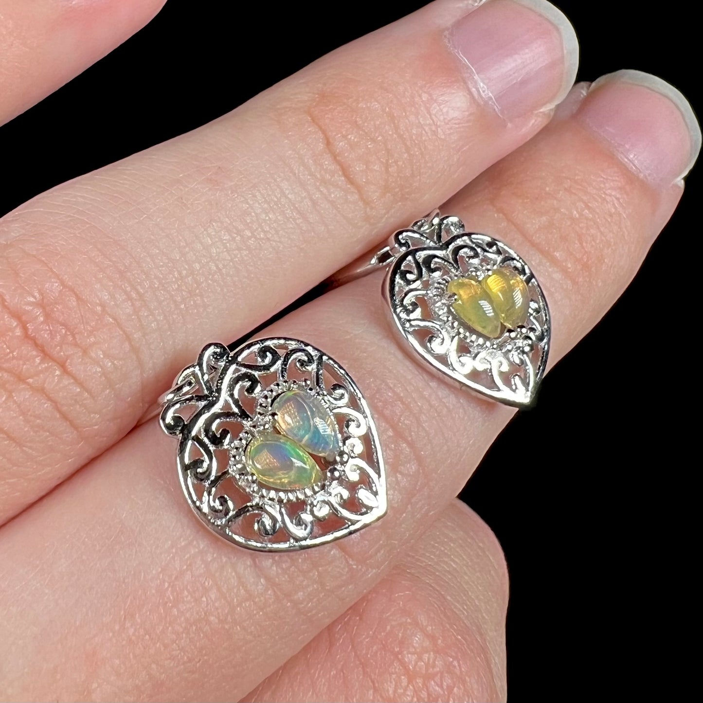 A pair of dangling sterling silver filigree heart earrings, each set with two Ethiopian opals.
