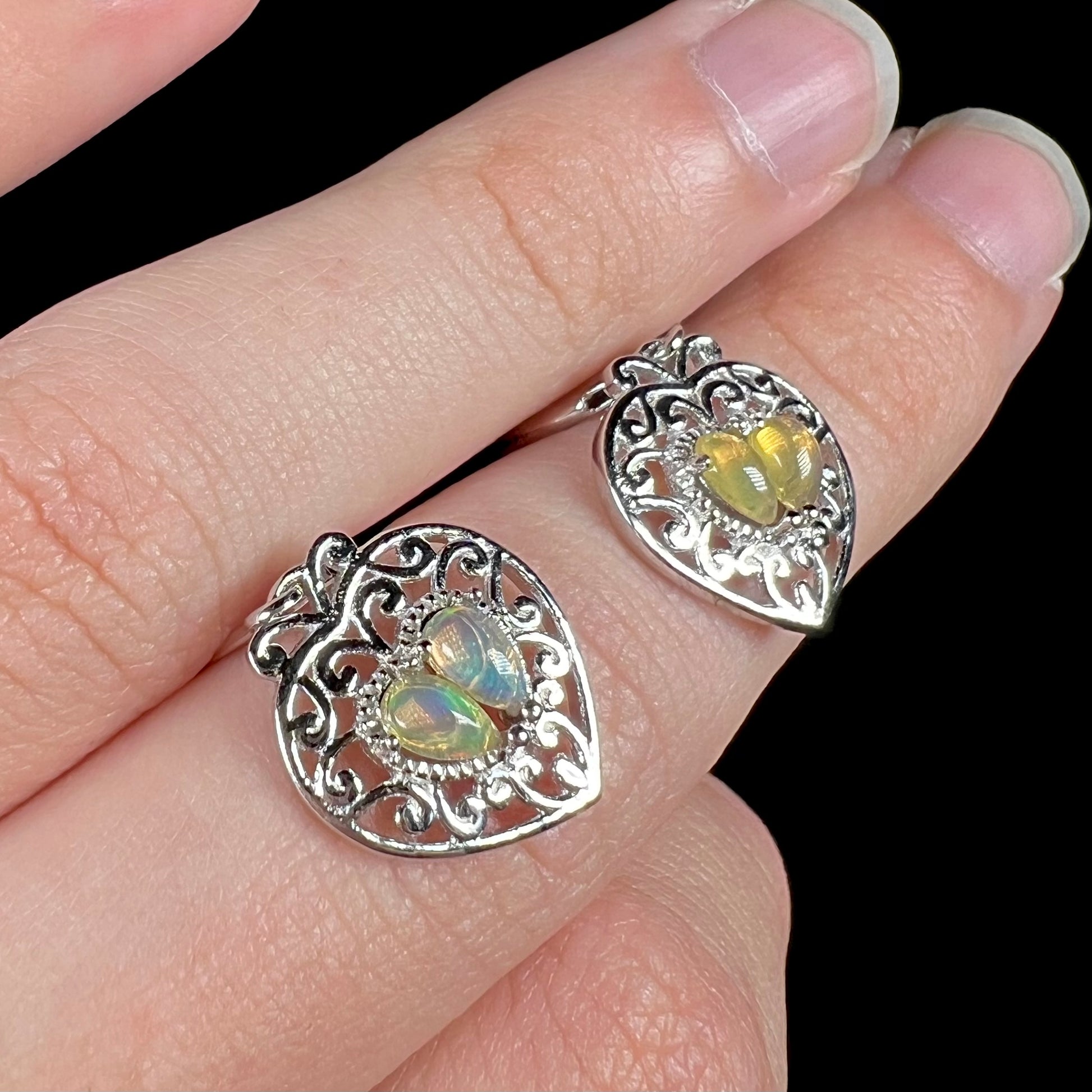 A pair of dangling sterling silver filigree heart earrings, each set with two Ethiopian opals.