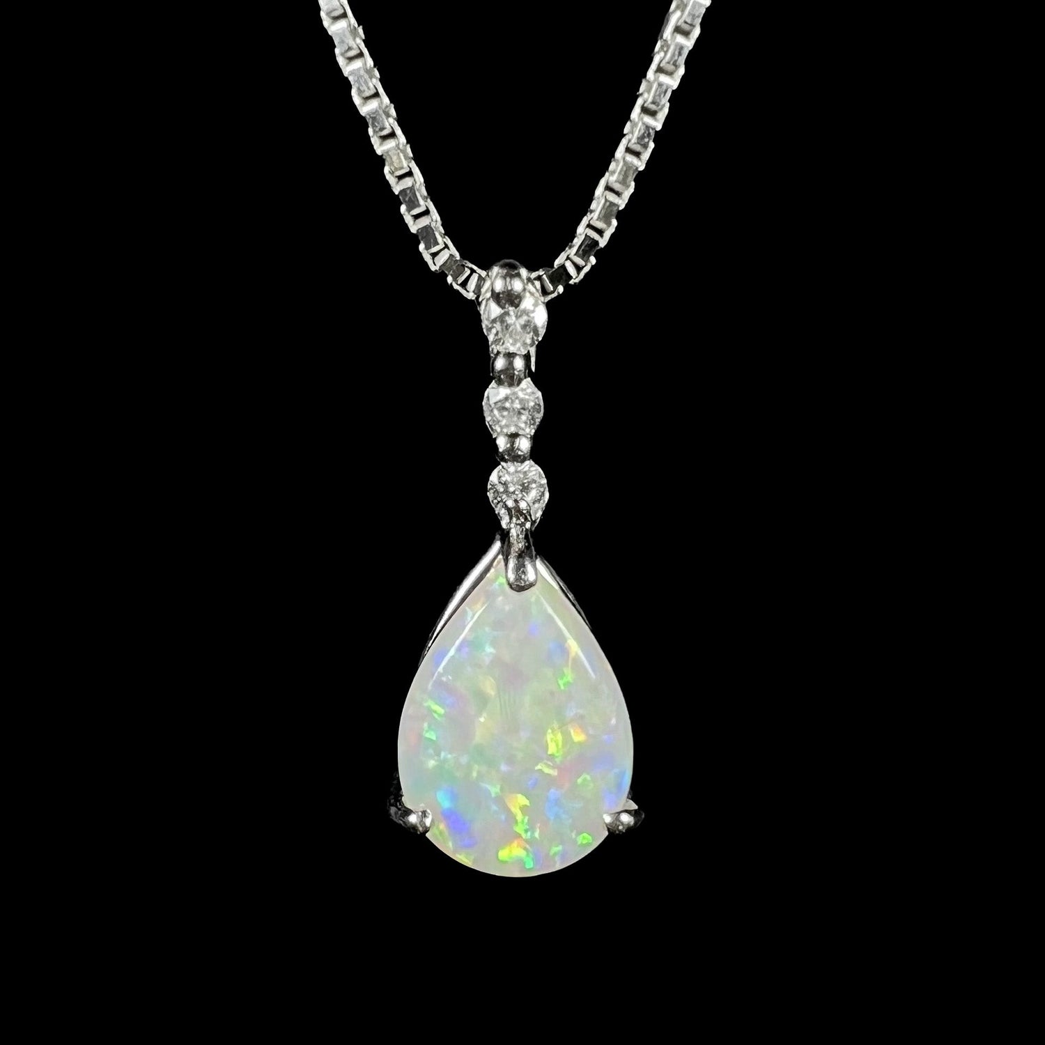 A platinum drop pendant mounted with three diamond accents and a pear shaped opal.