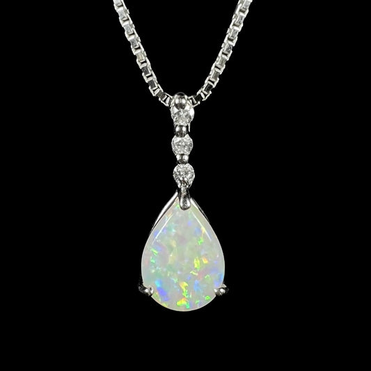 A platinum drop pendant mounted with three diamond accents and a pear shaped opal.