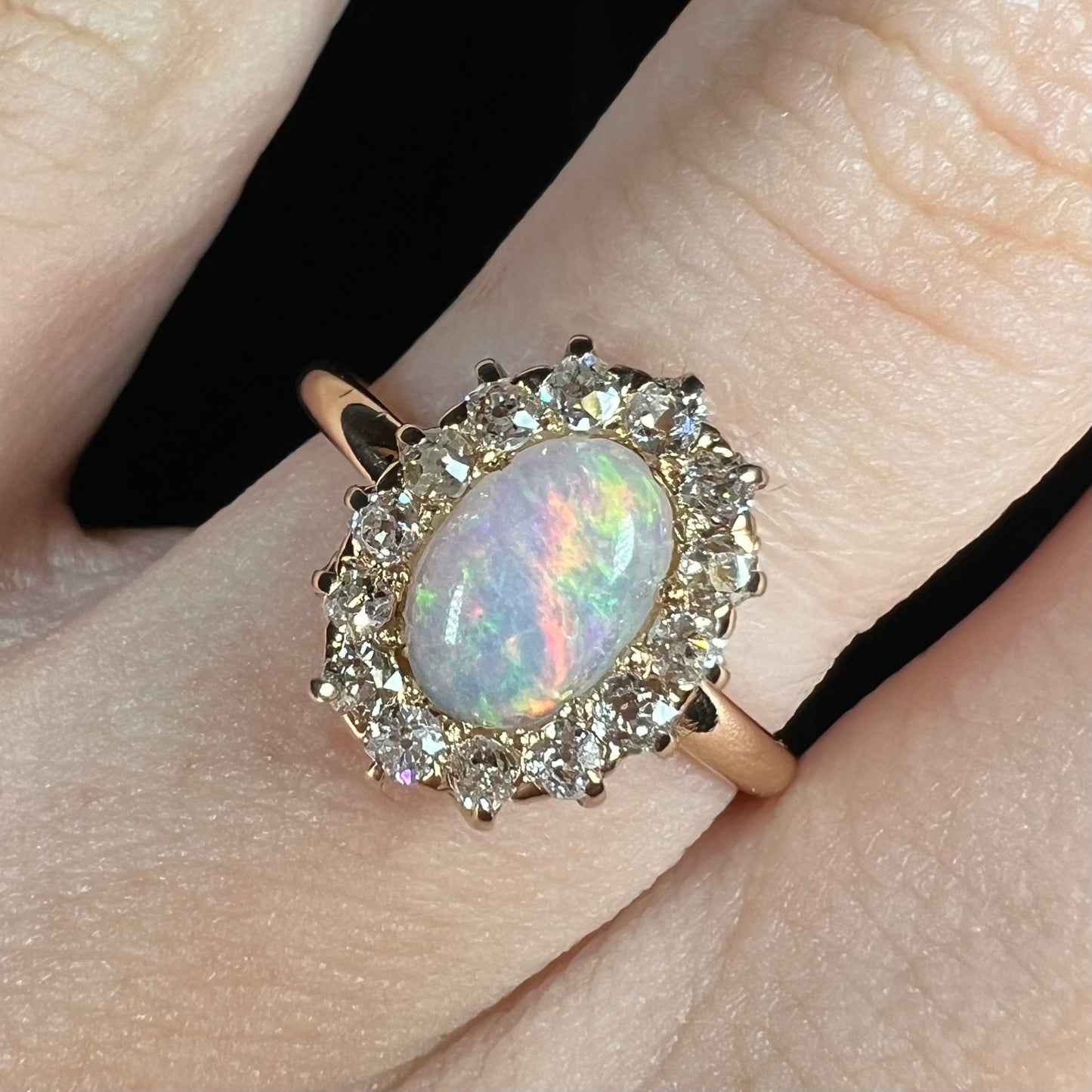 Close-up of a vintage opal and diamond halo engagement ring.  The ring is Edwardian style and set with Old Euro cut diamonds.