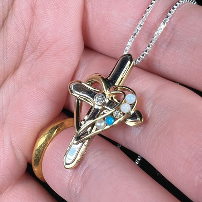 A two-tone sterling silver mother's cross necklace set with diamond, opal, turquoise, and pearl.