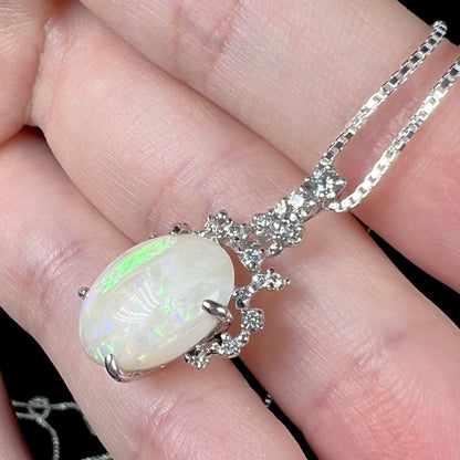 A side view of an opal and diamond necklace, where a thin green stripe is present at the top of the opal.