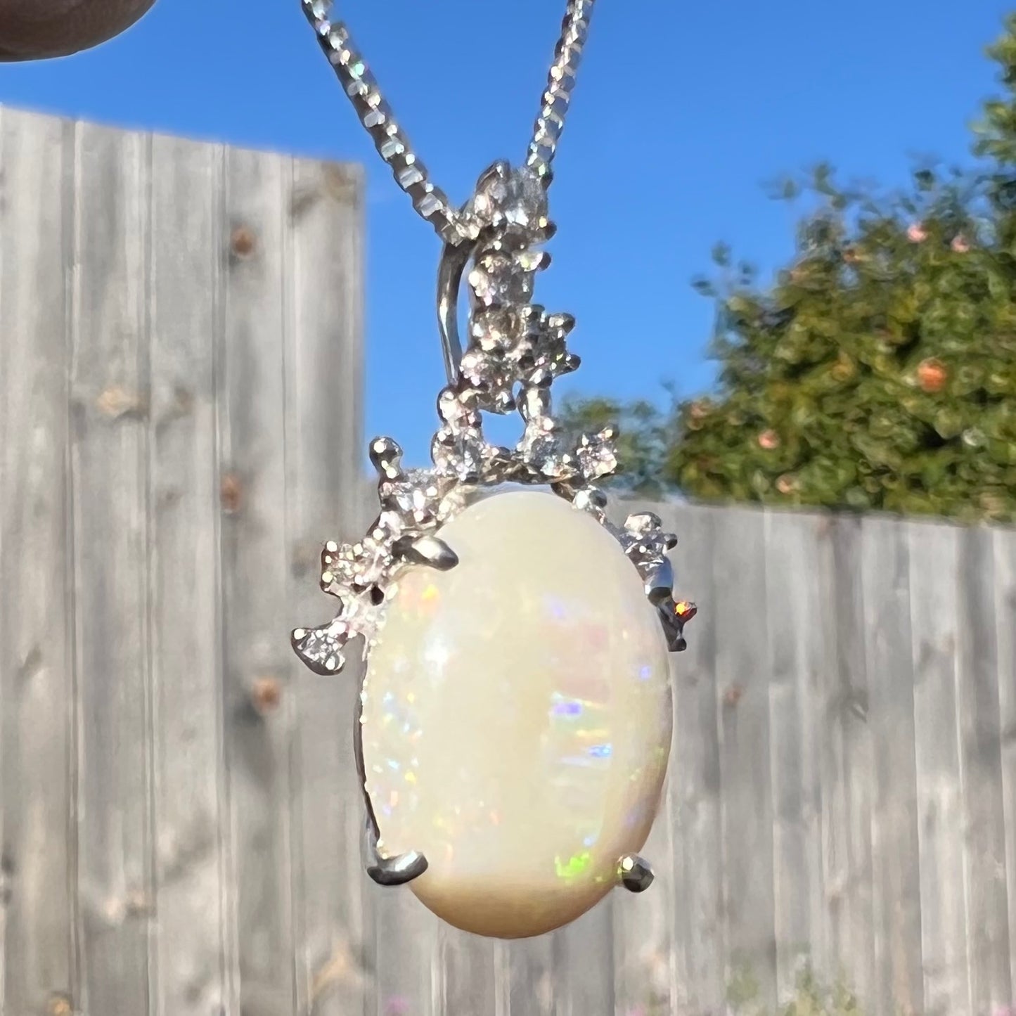 A macro view of an opal and diamond necklace outside at a twisted angle, with almost no visible flashes.