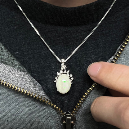 An opal and diamond necklace worn around the neck on a black T-shirt, showing a hint of green flash.