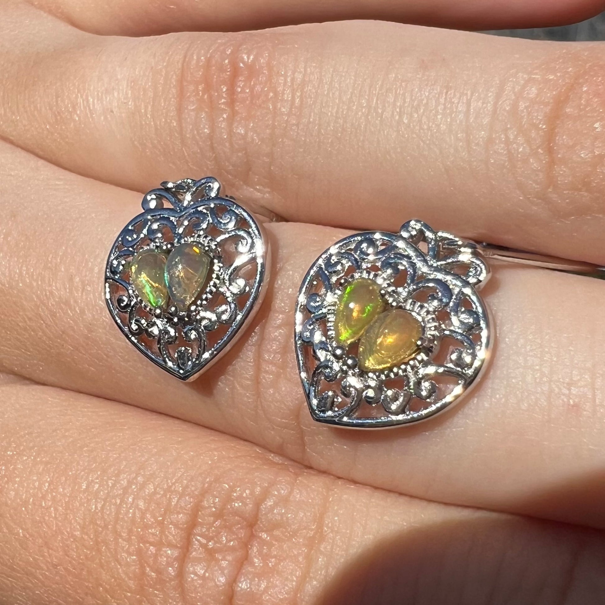 A pair of dangling sterling silver filigree heart earrings, each set with two Ethiopian opals.
