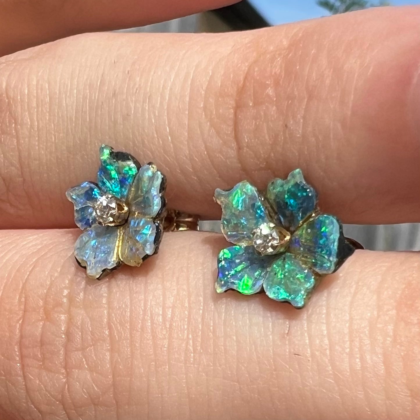 A pair of green carved boulder opal doublet flower earring jackets with gold CZ studs shown from a close-up angle in the sunlight.