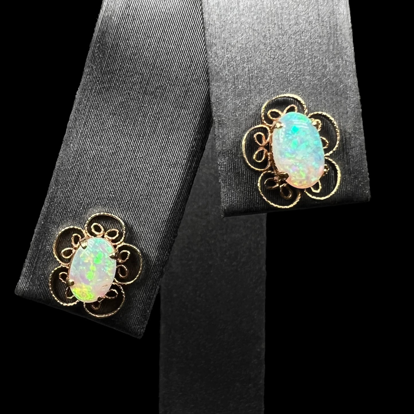 Front view of 14k gold Australian crystal opal filigree flower earrings on earring display