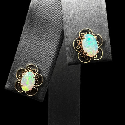 Front view of 14k gold Australian crystal opal filigree flower earrings on earring display