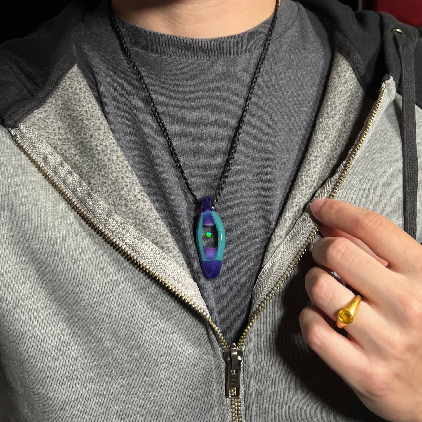An opal in glass necklace from artist Nathan Snyder's "Opal Geode" pendant line, worn around a model's neck against a dark shirt.
