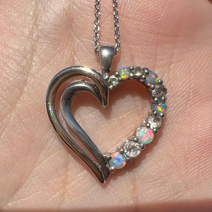 Close-up of a two-tone sterling silver and yellow gold lab-created opal and CZ heart necklace in sunlight.