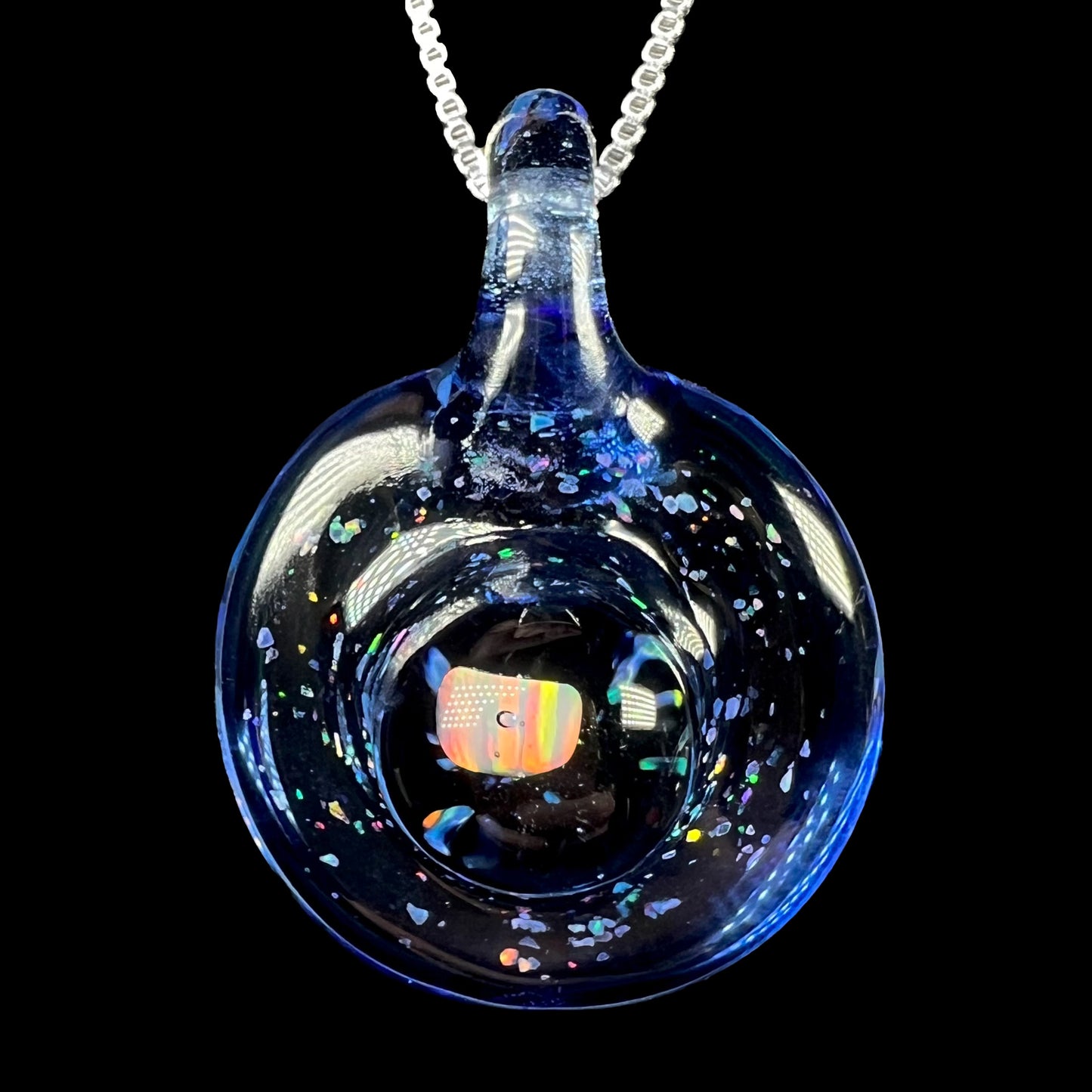 A lab-created opal in blue glass pendant by Michigan artist, Cameron Scott, shown close-up on a silver chain against black background.