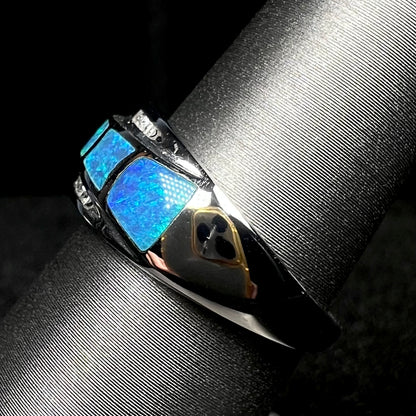 Side view of a blue opal inlay ring with diamond accents in 14k white gold, shown on ring display, the ring's polished shank in focus