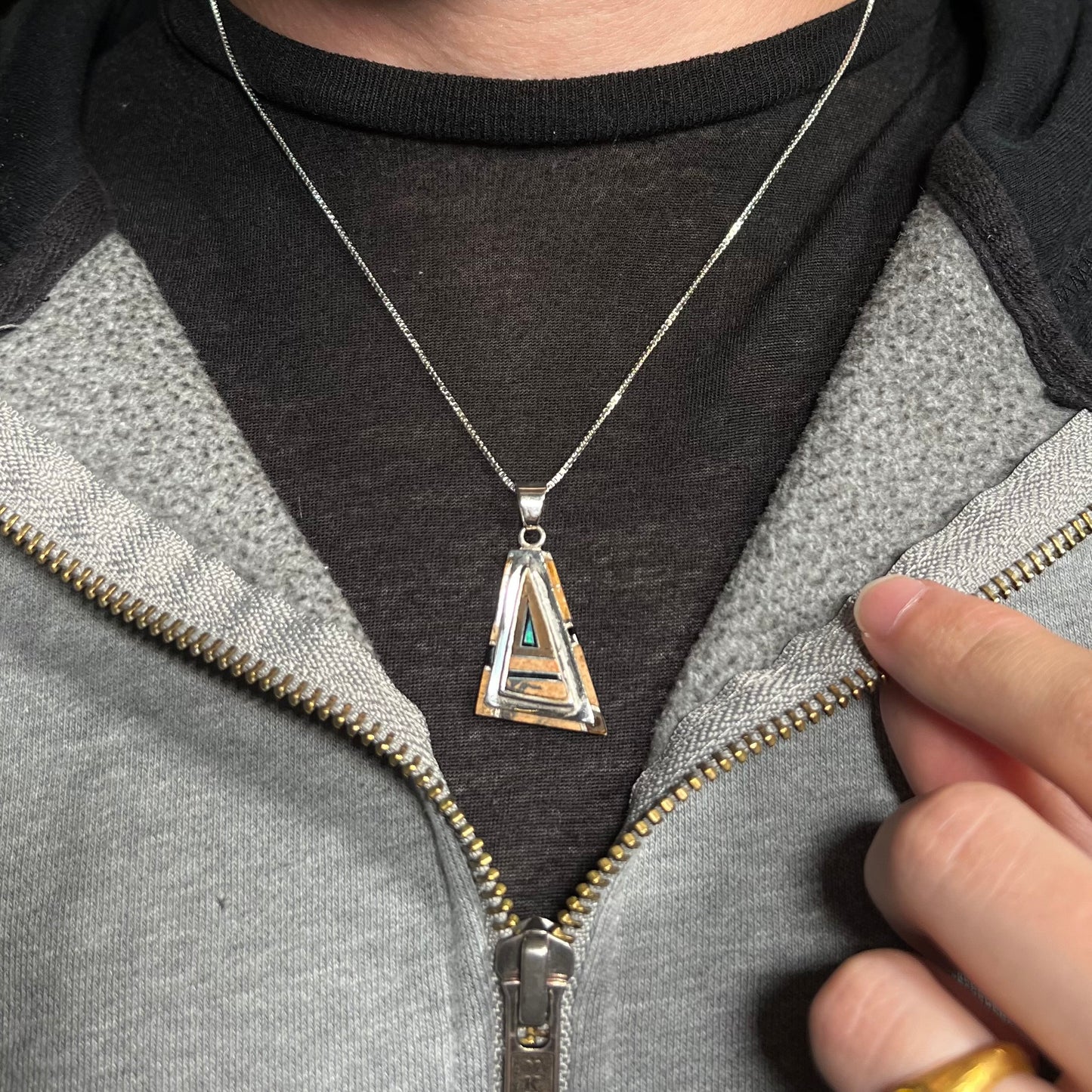 A sterling silver Australian opal, picture jasper, and onyx inlay necklace, worn around a neck against a dark shirt.