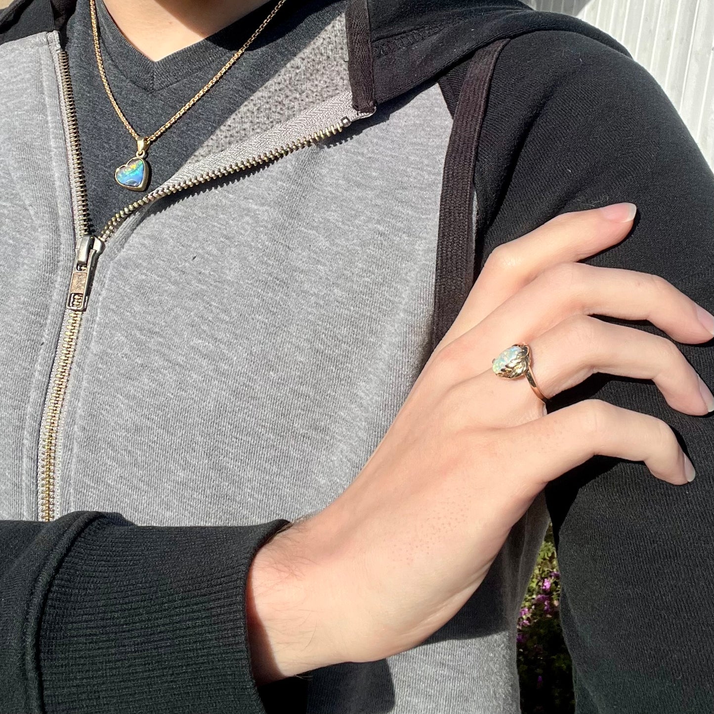 An gold opal ring with a leaf design, worn on a model's hand.