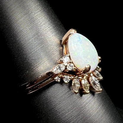 Teardrop shaped opal and moissanite wedding ring set in 14k rose gold, shown on ring display