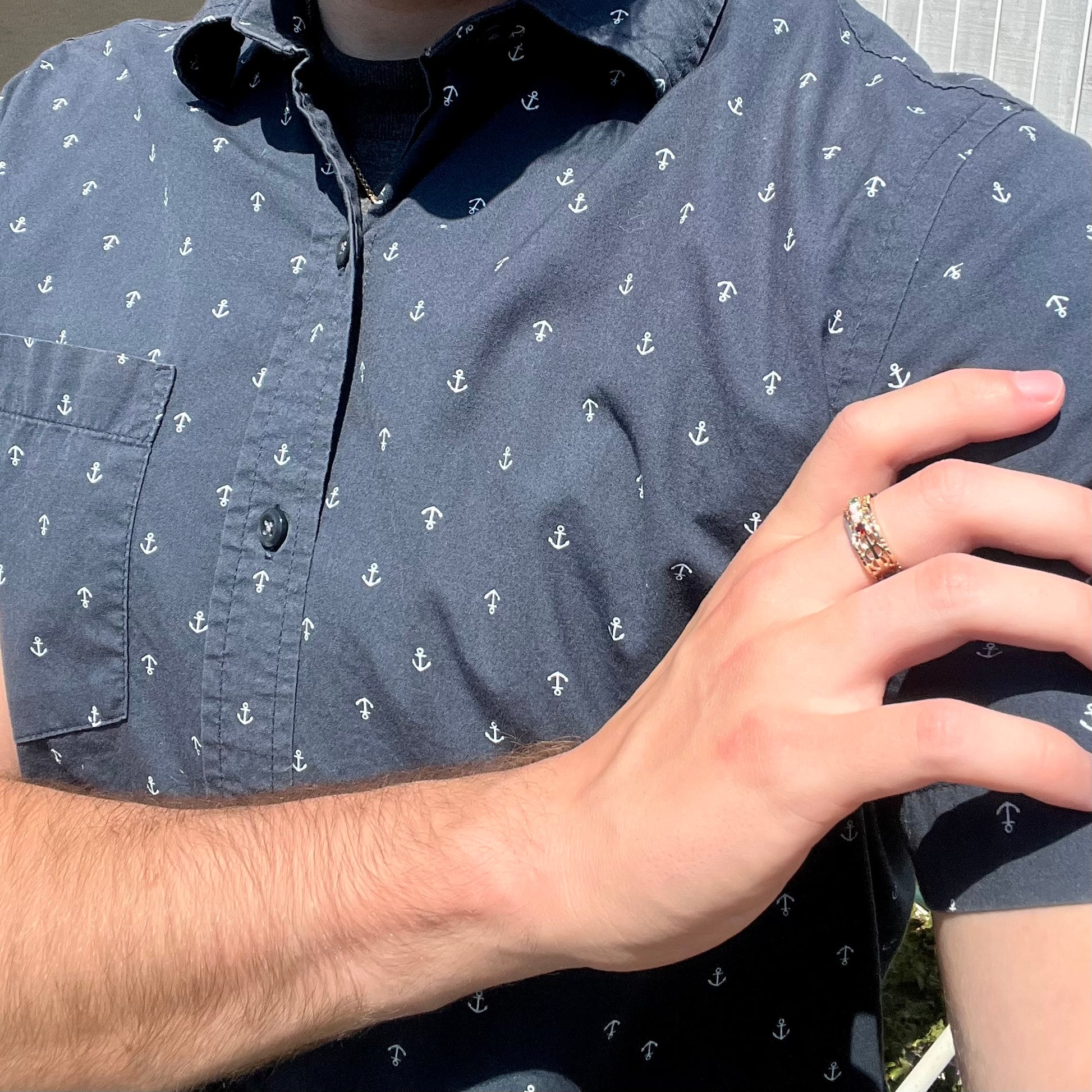 A gold opal, garnet, and emerald mother's ring, worn on a hand as it rests on the model's opposing shoulder.