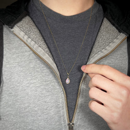 Opal necklace worn at its longest setting over a black T-shirt with a partially zipped sweatshirt. A very faint red flash is visible.