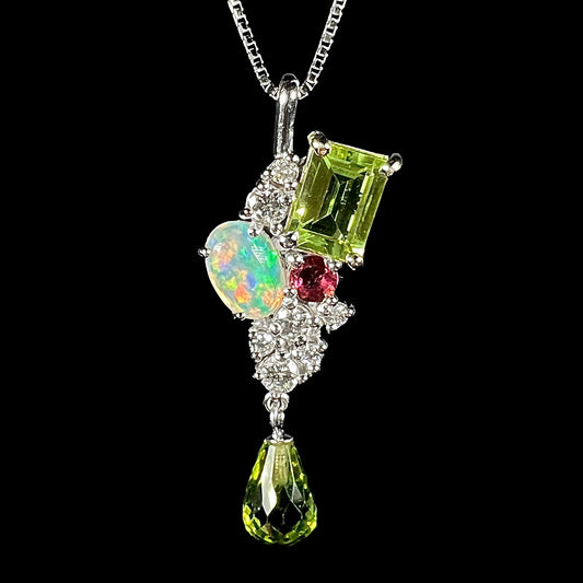 A ladies' white gold cluster gemstone necklace mounted with peridot, diamonds, purple sapphire, and an opal.