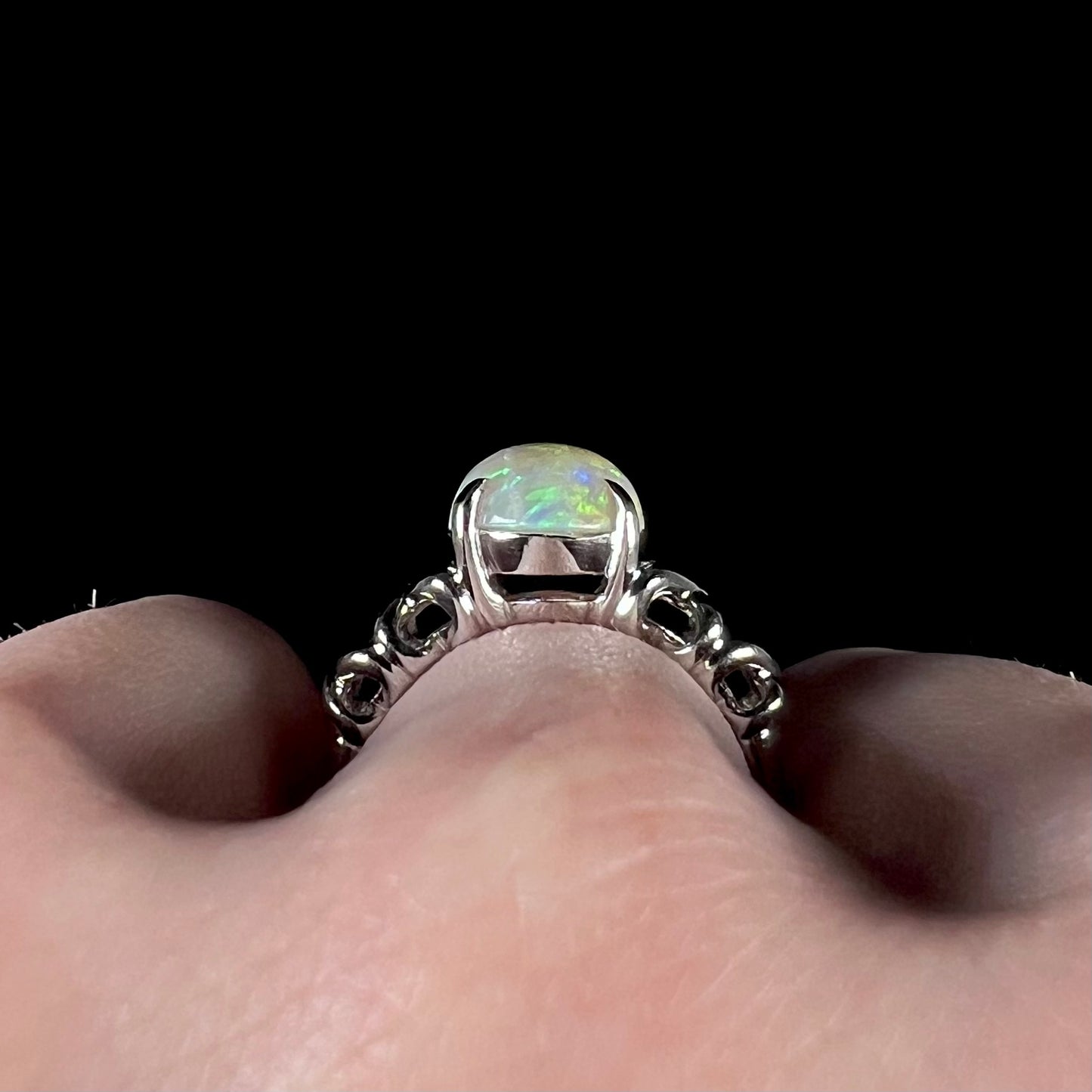 The gallery view of a platinum opal ring on a finger.