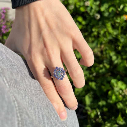 A sterling silver floating-style ring mounted with a black opal triplet in a halo of tanzanite stones.