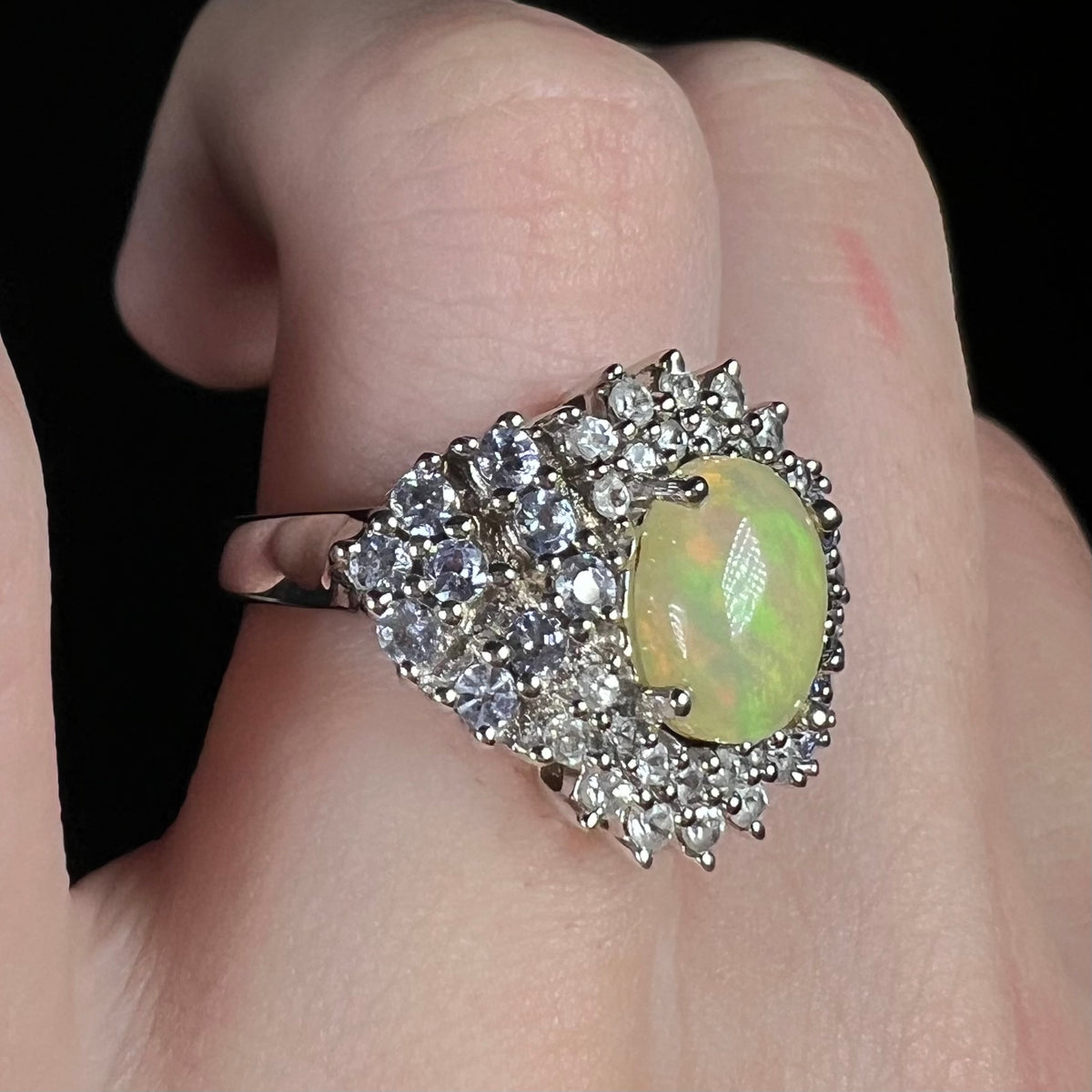 Ethiopian opal ring with tanzanite accents, worn on finger