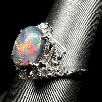 Side shoulder view of a dark opal ring set with geometric halo of diamond accents.  Round and tapered baguette cut diamonds in view.