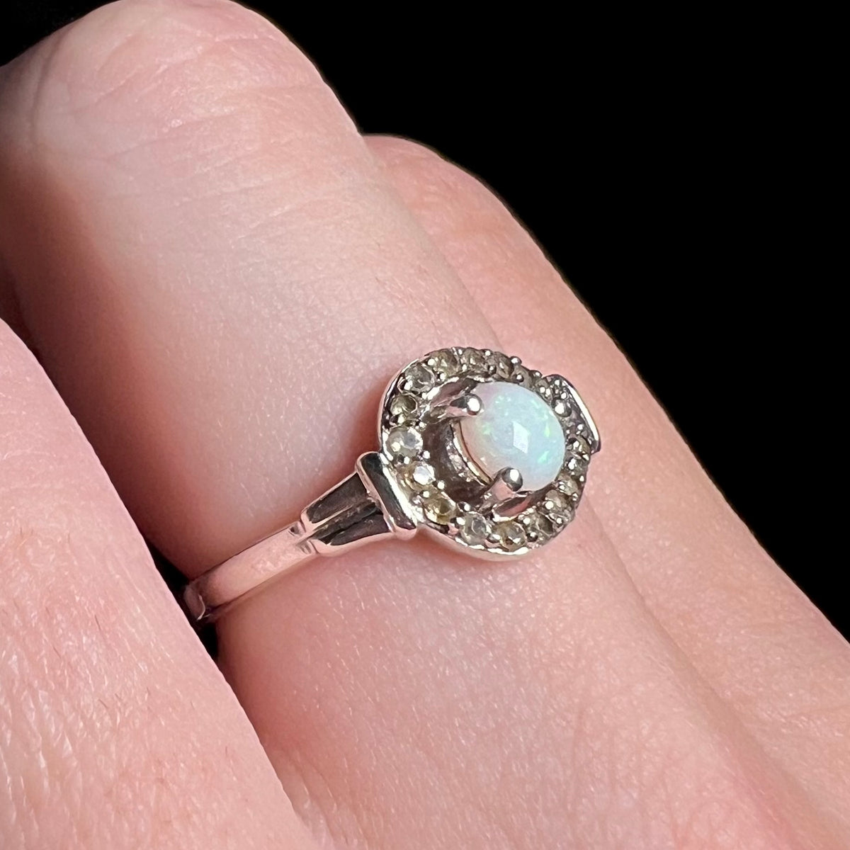 A white Australian opal and smoky quartz ring in sterling silver viewed close-up from angle on person's finger